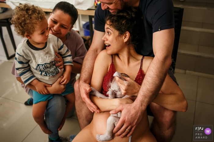 Photo by: <a href="https://www.fpja.com/documentary-family-photography-contests/adriana-costa/belo-horizonte/2110619">Adriana Costa - Brazil</a> MG at home birth photo session in a documentary-style showing a Child looks suspiciously at his brother who was just born
