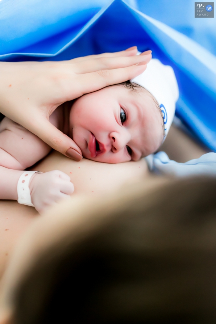 Photo by: <a href="https://www.fpja.com/documentary-family-photography-contests/ellen-brito/sao-paulo/2111355">Ellen Brito - Brazil</a> Maternidade Pro Matre hospital documentary birth photography of a newborn looking to say Hi mommy