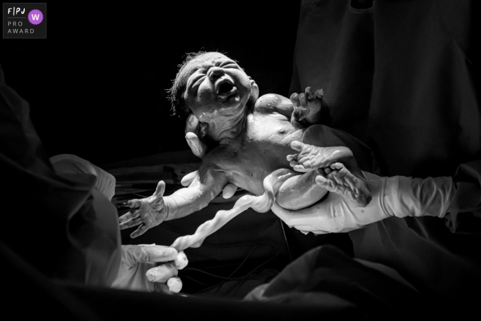 Photo by: <a href="https://www.fpja.com/documentary-family-photography-contests/liliane-cotta/rio-de-janeiro/2111499">Liliane Cotta - Brazil</a> Maternidade Perinatal Barra hospital birth photo of a doctor showing everyone the baby just come out of mom's belly