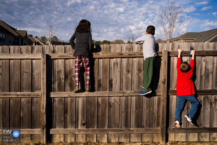 Atlanta Day in the Life Session of documentary family photography of children climbing a fence