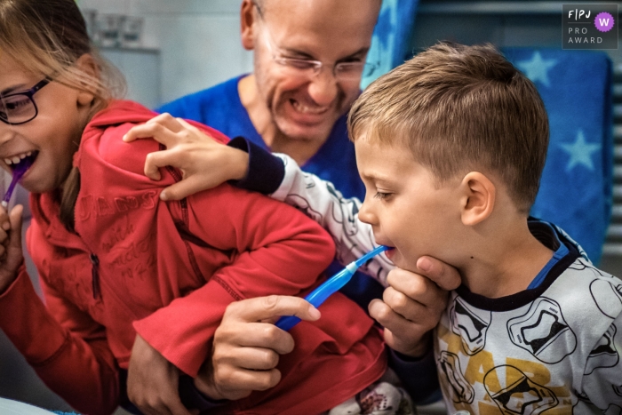 Photo by: <a href="https://www.fpja.com/documentary-family-photography-contests/katrin-k%C3%BCllenberg/dusseldorf/2110434">Katrin Küllenberg - Germany</a> Dusseldorf Day in the Life documentary family photo showing dad helping with Cleaning teeth