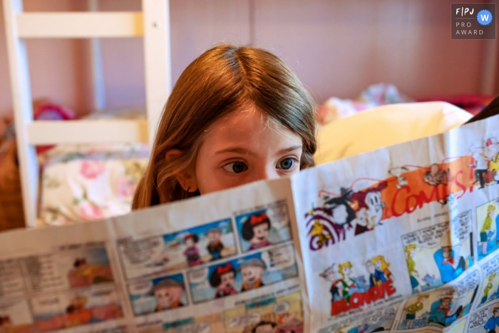 Photo by: <a href="https://www.fpja.com/documentary-family-photography-contests/nick-otto/san-francisco/2110476">Nick Otto - United States</a> SF at home Day in the Life photography of a girl reading the comics