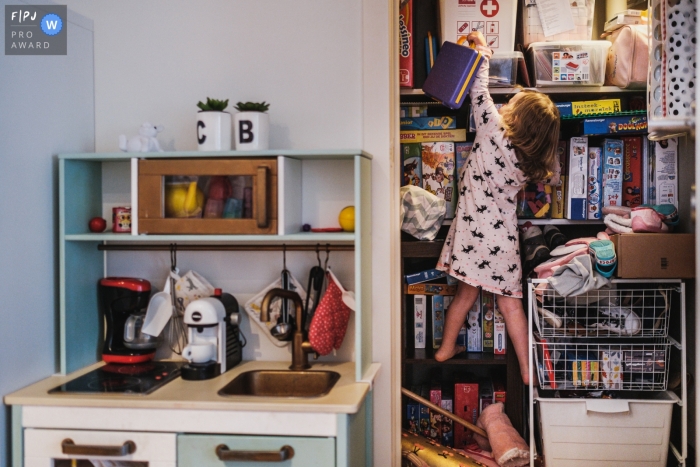 Photo by: <a href="https://www.fpja.com/documentary-family-photography-contests/christophe-de-mulder/antwerpen/2110554">Christophe De Mulder - Belgium</a> Antwerpen at home Day in the Life photography showing the Daughter trying to get her favorite toy by climbing in the closet