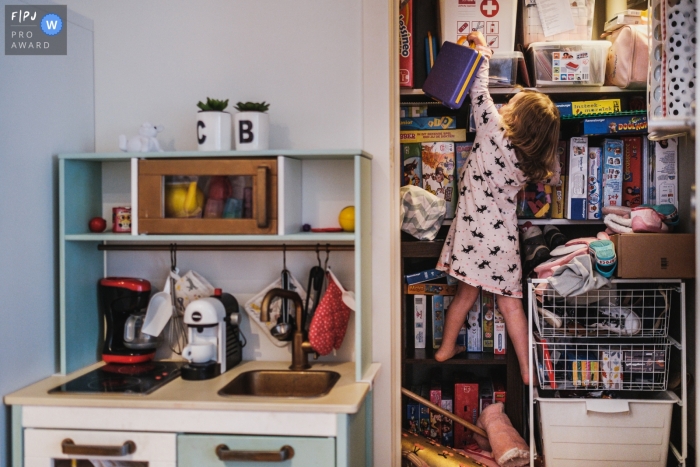 Anvers à la maison Photographie de jour dans la vie montrant la fille essayant d'obtenir son jouet préféré en grimpant dans le placard