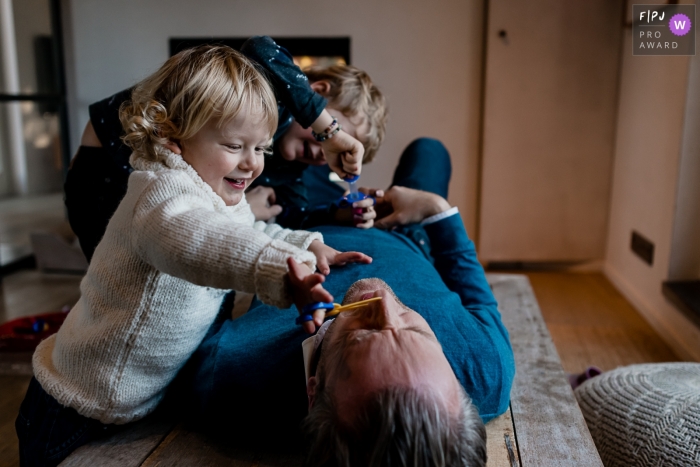 Séance de photographie Day in the Life à domicile en Wallonie avec les enfants jouant au docteur en utilisant papa comme patient