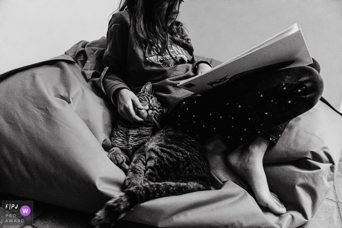 Wallonie Day in the Life documentary family photo of a child reading a book in a bean bag chair while petting a cat Wallonie Day in the Life documentary family photo of a child reading a book in a bean bag chair while petting a cat