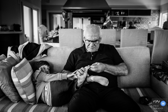 Photo by: <a href="https://www.fpja.com/documentary-family-photography-contests/graziela-ventura/sao-paulo/2110834">Graziela Ventura - Brazil</a> Day in the Life Sao Paulo documentary family photography session with Grandpa checking on the childs feet