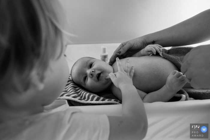 Photo by: <a href="https://www.fpja.com/documentary-family-photography-contests/rose-dedman/bath/2111317">Rose Dedman - United Kingdom</a> Somerset at home Day in the Life photography showing a Big sister pokes her baby brother