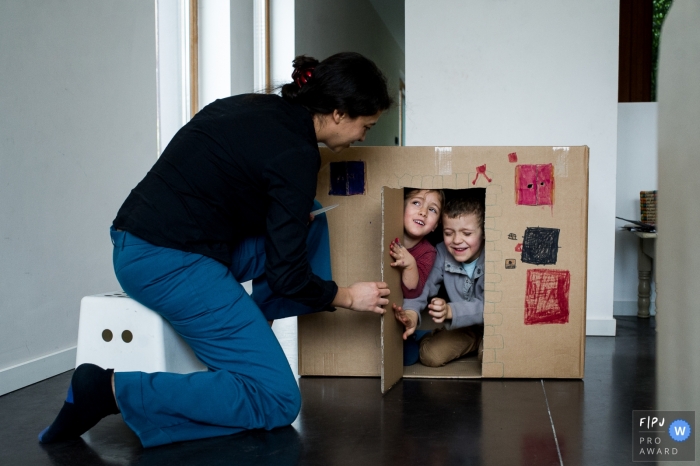 East Flanders at home Day in the Life photography with mom playing house with kids in a cardboard box East Flanders at home Day in the Life photography with mom playing house with kids in a cardboard box