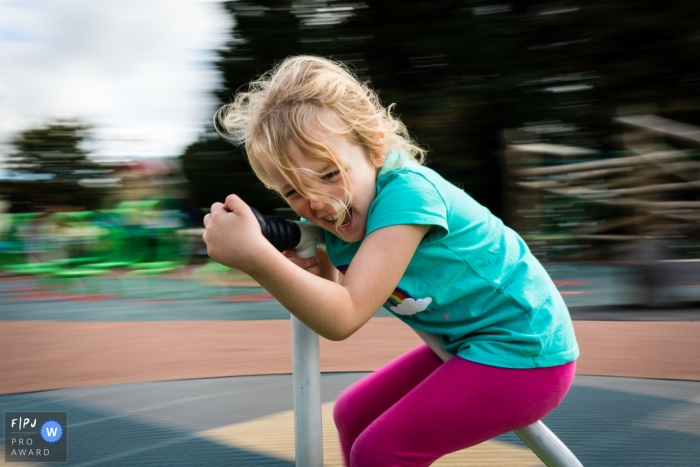 Photo by: <a href="https://www.fpja.com/documentary-family-photography-contests/alice-chapman/cambridgeshire/2111507">Alice Chapman - United Kingdom</a> Cambridgeshire, England Day in the Life documentary family photo from the park of a girl on roundabout