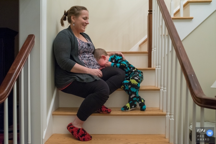 Journée dans la vie, dans le Connecticut, séance de photographie de famille documentaire d'un jeune garçon en crise alors que maman le console alors qu'ils sont assis dans les escaliers