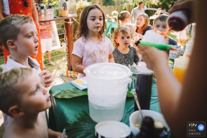 Photo by: <a href="https://www.fpja.com/documentary-family-photography-contests/ron-storer/seattle/2111832">Ron Storer - United States</a> Seattle, WA documentary family photo of children eagerly waiting for flavored shaved ice