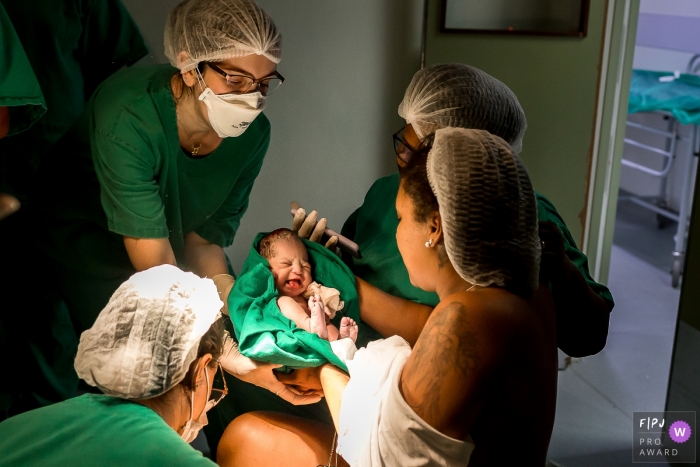 Moment-driven Hospital Unimed Campos birth photography of a mother handing baby over the a pediatrician