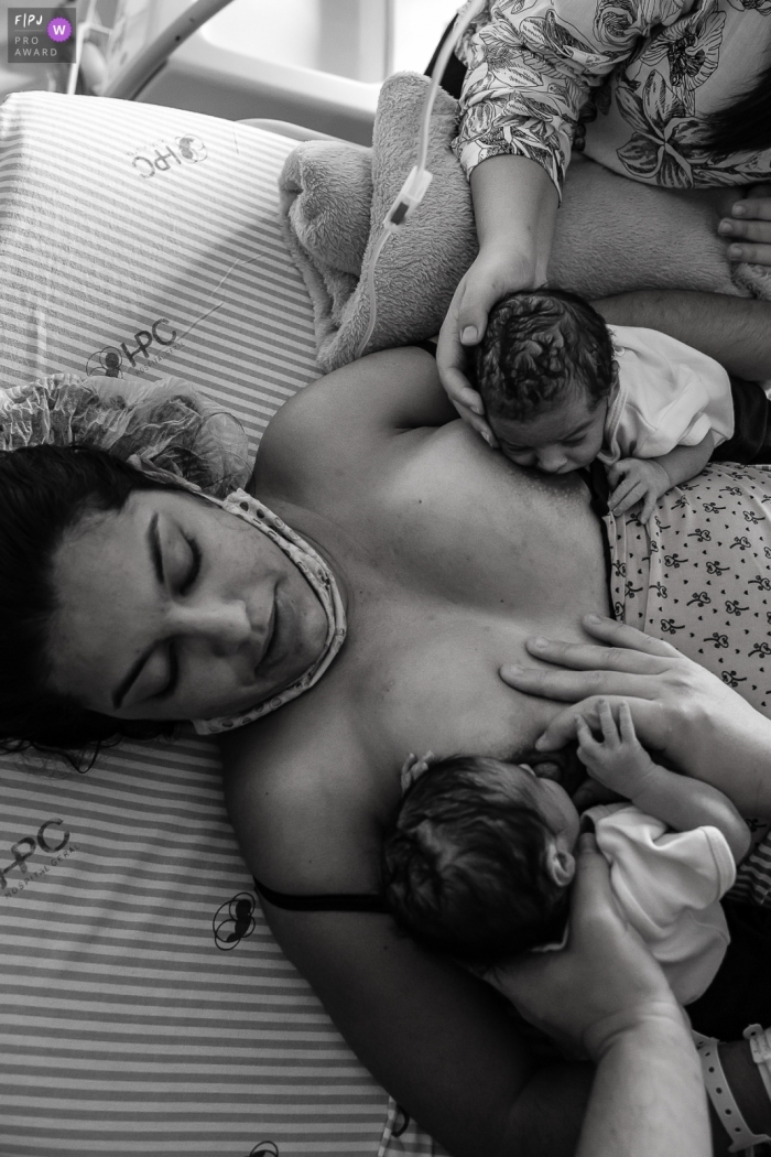 Moment driven Hospital Plantadores de Cana birth photojournalism image of a mother breastfeeding both of her new twin babies