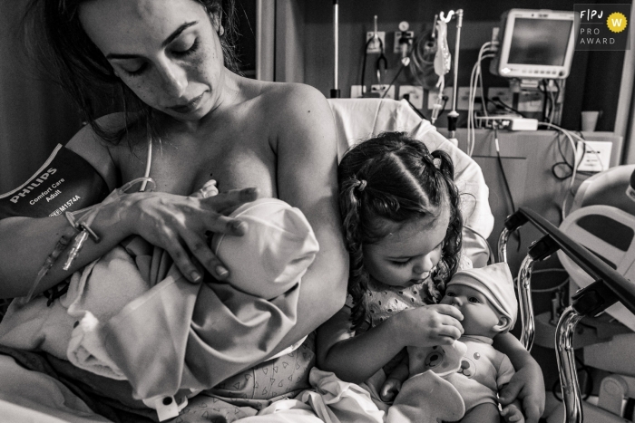 Image de photojournalisme de naissance à l'hôpital Albert Einsten d'une mère qui allaite avec sa fille aînée sur le côté après l'accouchement