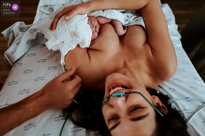 Moment driven São Luiz Itaim birth photojournalism image of a mother with her child on her lap after birth Moment driven São Luiz Itaim birth photojournalism image of a mother with her child on her lap after birth