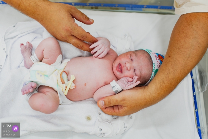 Moment driven Santa Joana birth photojournalism image of a little baby with big hands holding it