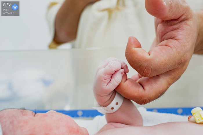 Moment-driven Santa Joana birth photography of a father holding the small gripping hand of his newborn child Moment-driven Santa Joana birth photography of a father holding the small gripping hand of his newborn child