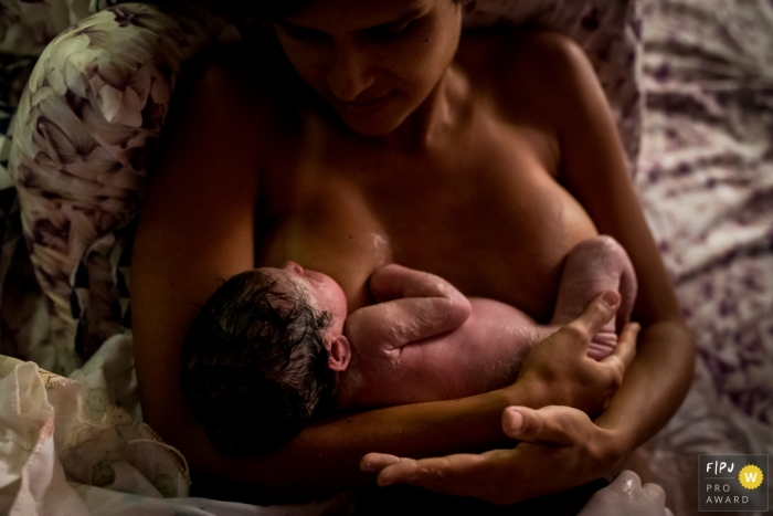 Moment driven at-home birth photojournalism image showing first Skin contact for the new baby Moment driven at-home birth photojournalism image showing first Skin contact for the new baby