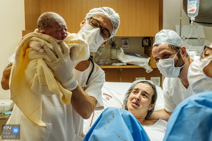 Moternidade Perinatal Barra, photojournalisme de naissance, image du médecin présentant le bébé à maman et papa