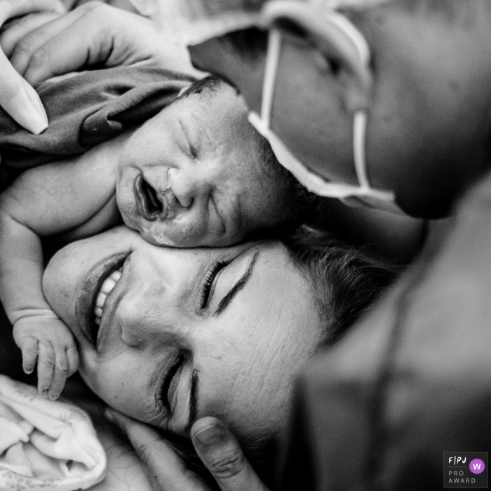 Moment driven Maternidade Santa Luiza birth photojournalism image showing the Golden hour with father and mother