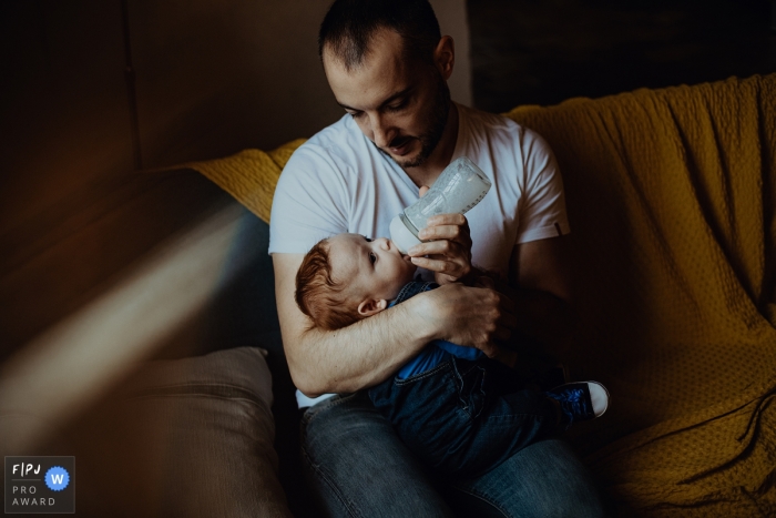 Photo by: <a href="https://www.fpja.com/documentary-family-photography-contests/david-pommier/lyon/2111919">David Pommier - France</a> Moment driven Lyon family photojournalism image of father feeding his child a bottle