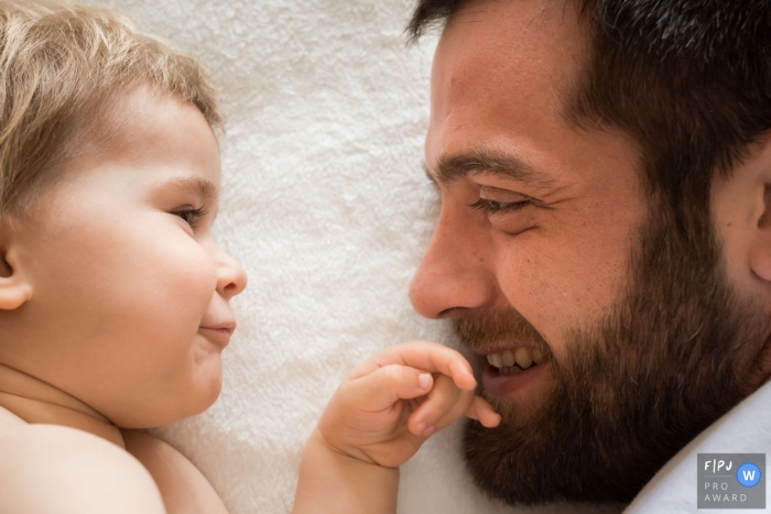 Image de photojournalisme familial des Landes, animée par un moment, d'un père et d'un fils allongés face à face