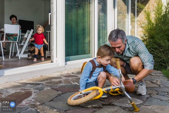 Photo by: <a href="https://www.fpja.com/documentary-family-photography-contests/kobe-vanderzande/limburg/2111952">Kobe Vanderzande - Belgium</a> Moment driven Limburg family photojournalism image of granfather fixing a bike with his grandson