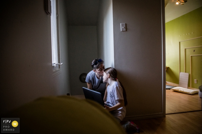Photo by: <a href="https://www.fpja.com/documentary-family-photography-contests/anabel-burin/montreal/2112063">Anabel Burin - Canada</a> Montreal family photo image. Part of the series I did on Single Mothers homes during the Covid-19 Pandemic. This image shows a mother and her daughter right after her online ballet class seeking physical contact during times of "virtual everything'