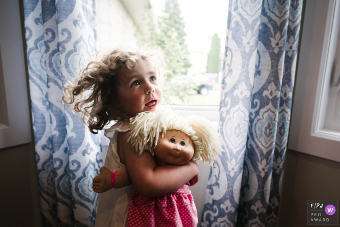 Photo by: <a href="https://www.fpja.com/documentary-family-photography-contests/viara-mileva/kingston/2112069">Viara Mileva - Canada</a> Moment driven Kingston family photojournalism image of a girl as she holds her favorite doll, who looks uncannily like her