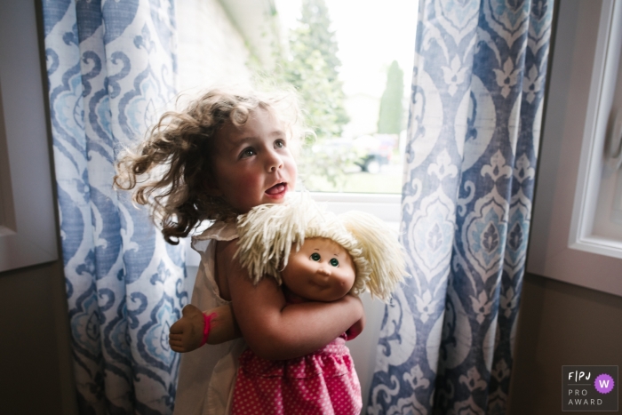 Image de photojournalisme familial de Kingston animée par un moment d'une fille alors qu'elle tient sa poupée préférée, qui lui ressemble étrangement