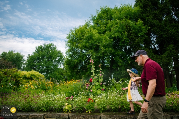Photo by: <a href="https://www.fpja.com/documentary-family-photography-contests/viara-mileva/kingston/2112070">Viara Mileva - Canada</a> Moment driven Ottawa family photojournalism image of a young girl exploring the flower gardens with her grandfather