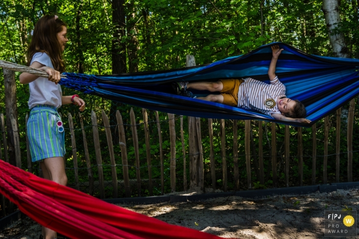 Moment driven Limburg family photojournalism image showing brother and sister fun on hammocks