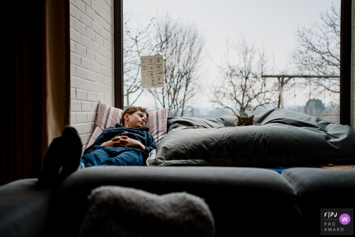 Image de photojournalisme familial de Wallonie animée par un moment capturant un adolescent en train de faire la sieste sur le canapé