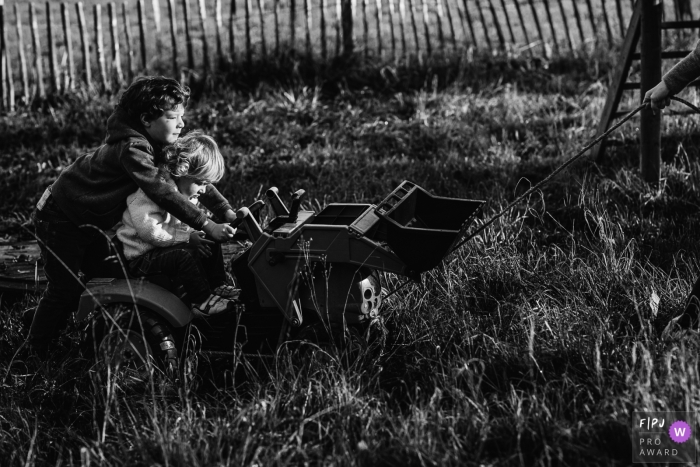 Photographie de famille wallonne animée par un moment d'un couple d'enfants conduisant un tracteur