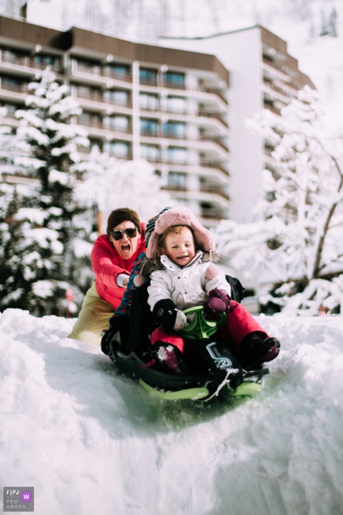 Moment-driven Savoie family photography of a mother with her two children sledding on the snow