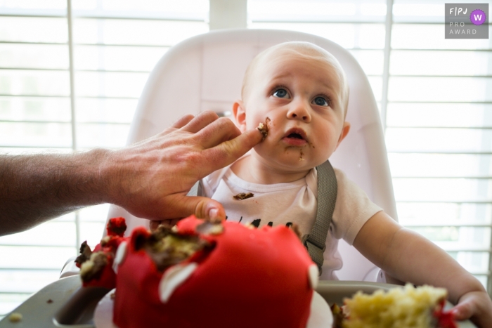 Moment-driven Atlanta family photography of a finger reaching in with cake frosting to the babies cheek Moment-driven Atlanta family photography of a finger reaching in with cake frosting to the babies cheek