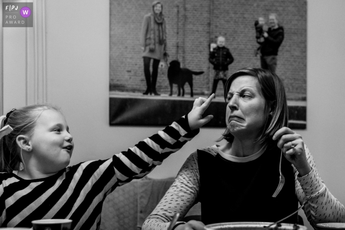 Image de photojournalisme de la famille Zwolle motivée par un moment d'un moment amusant entre maman et fille, regardez l'image "parfaite" en arrière-plan