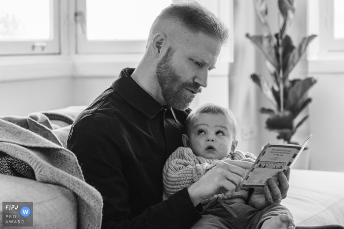 Moment-driven Amsterdam family photography of a boy watches his dad reading to him Moment-driven Amsterdam family photography of a boy watches his dad reading to him