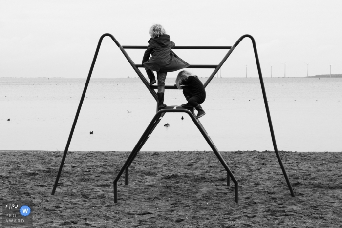 Moment-driven Amsterdam family photography of two children playing on a climbing frame