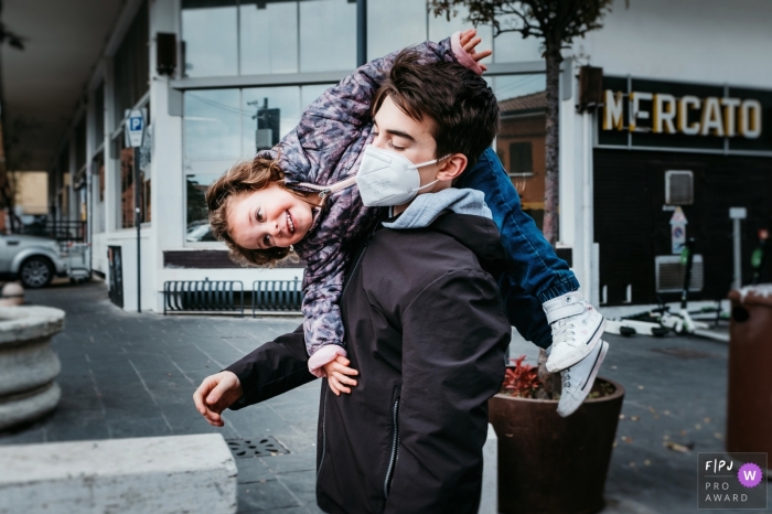 Moment-driven Liguria family photography of a big brother carrying his little sister over his shoulder Moment-driven Liguria family photography of a big brother carrying his little sister over his shoulder