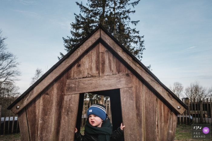 Image de photojournalisme familial belge animée par un moment d'un petit garçon jouant dans une petite maison