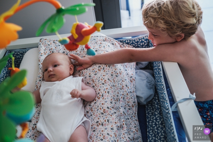 Moment-driven Antwerpen family photography of a little boy that wants contact with his baby sister