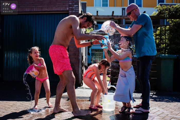 Image de photojournalisme de famille Noord Brabant animée par un moment d'une famille jouant dans l'eau par une chaude journée