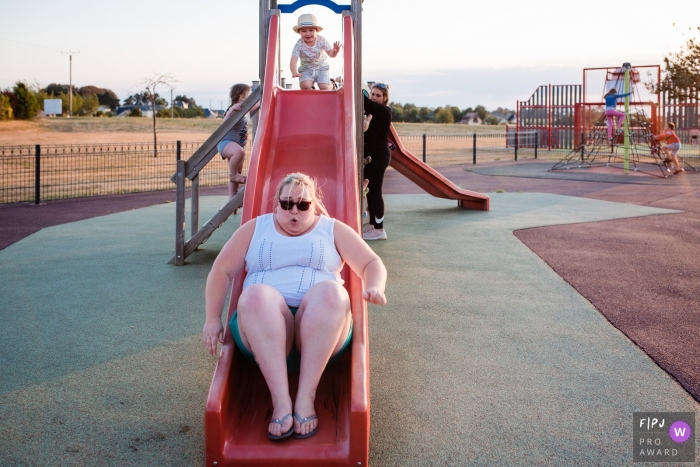 Moment driven Noord Brabant family photojournalism image of a mother and child on a slide at the playground