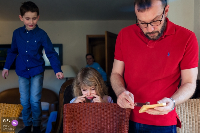 Moment driven Paris family photojournalism image of a father making toast for his waiting children Moment driven Paris family photojournalism image of a father making toast for his waiting children
