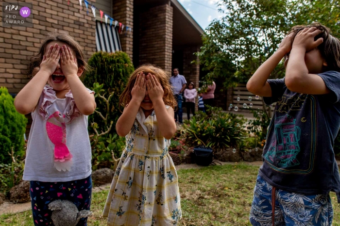 Moment driven Melbourne family photojournalism image of kids covering their eyes during a hide and seek session