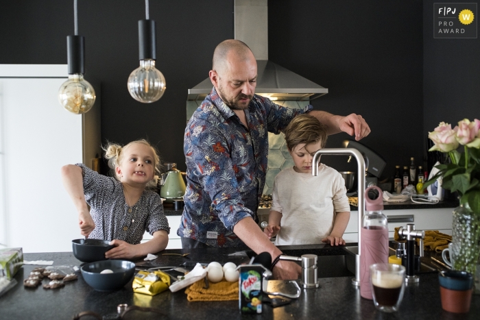 Moment-driven Orlando family photography of child and mess synonymous with freedom of expression Moment driven Drenthe family photojournalism image of a father and children cooking in the kitchen