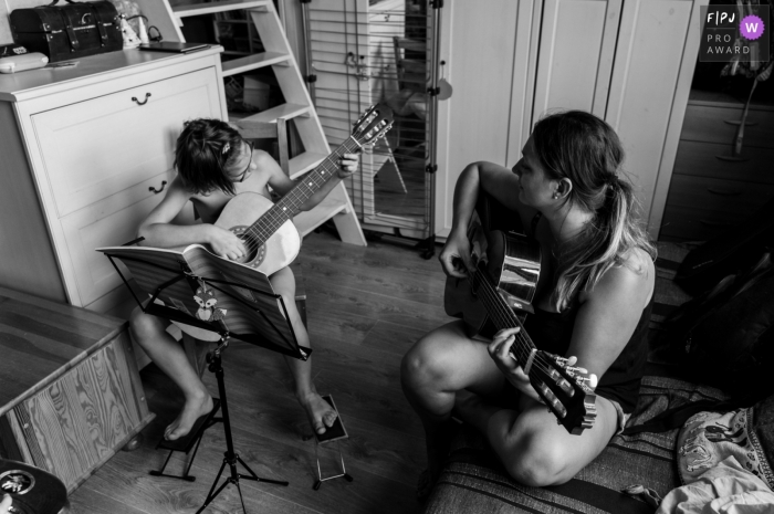 Moment-driven Gard family photography of a mom teaching her son how to play the guitar