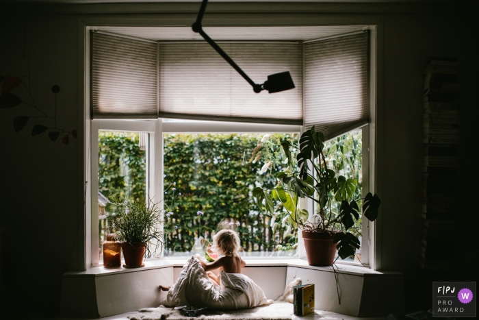 Moment-driven Drenthe family photography of a young child looking outside the window